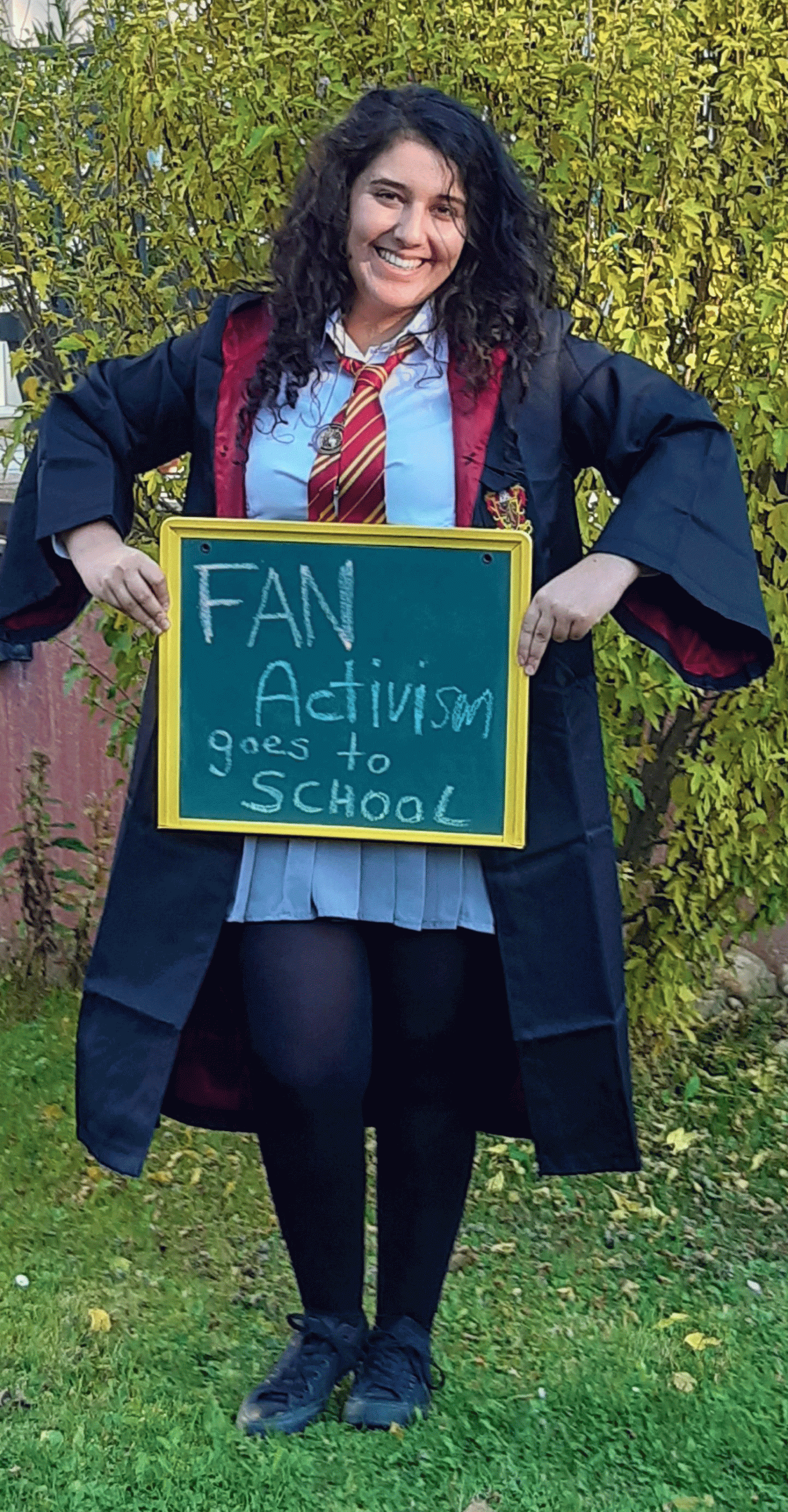 Junge Dame in Harry Potter Outfit hält eine kleine Tafel, auf der "Fan activism goes to school" steht